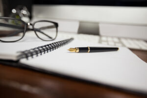 spiral notepad with pen and reading glasses